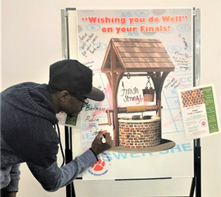 A student at the Whitehaven Center writes an encouraging message to classmates on the interactive Wishing Well during Fuel for Finals. 