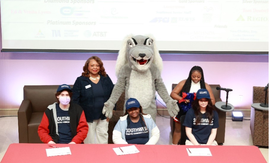 Aiden Gibson, Kabreyia Wilson and Jayden Hunting (front row) prepare to sign their NC(3) commitment letters as President Tracy D. Hall and Saluqi cheerleader Brianna Cole cheer them on. 