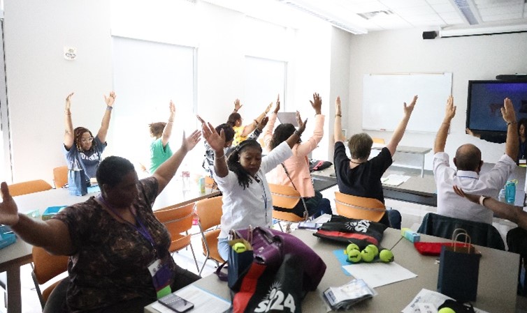 Faculty and staff learn stretching techniques to relieve tension during a desk yoga session. 