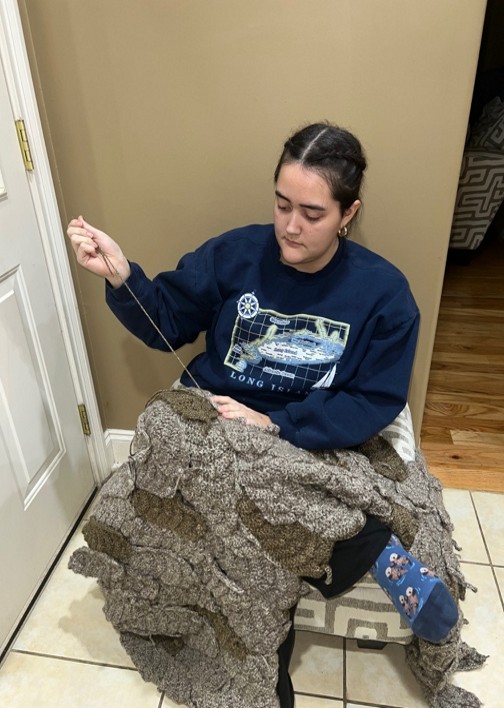 Taylor Waltz working on her crocheted version of the feathered cloak of the Norse goddess Freya.