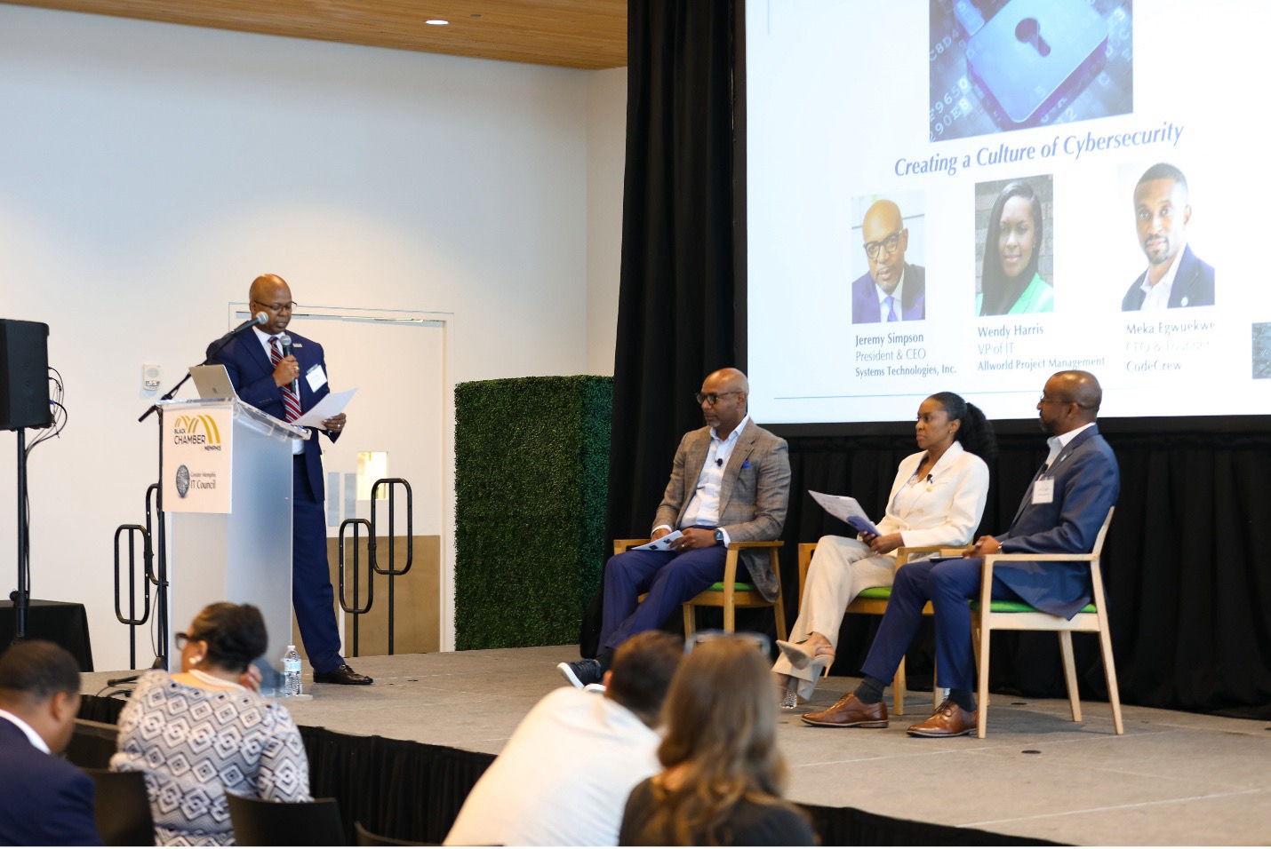 Dr Boyd moderating 3 panelists on a stage