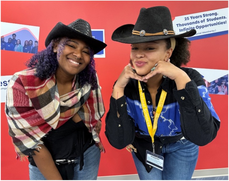 Two women wearing cowboy hats and dressed in western attire posing
