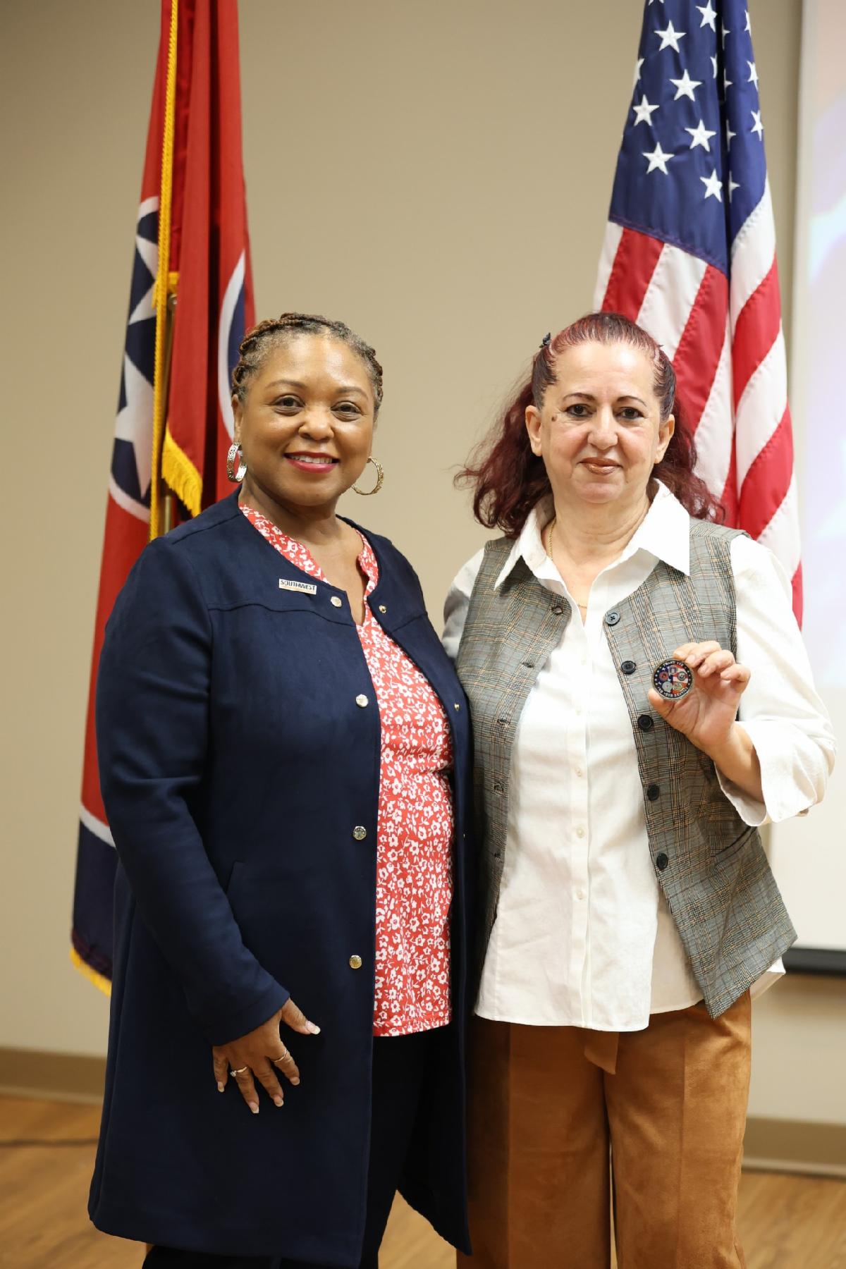 Esma standing next to Dr. Hall in front of Tennessee and United States flags